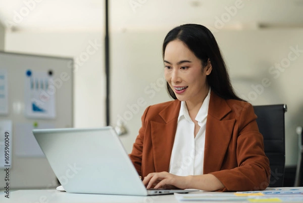 Fototapeta Businesswomen hand working with tablet and laptop computer with documents on office desk in modern office.