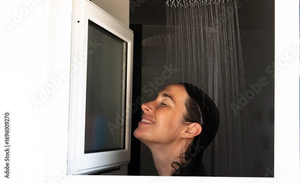 Fototapeta Smiling woman taking a shower and enjoying the moment of relaxation