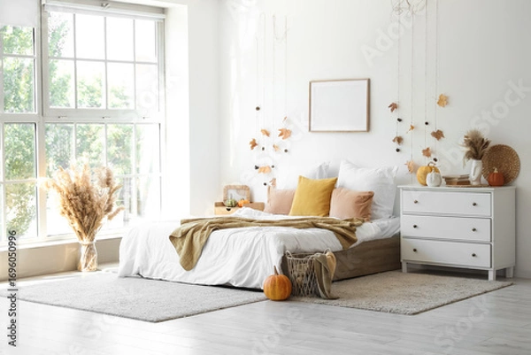 Fototapeta Interior of light bedroom with autumn leaves, pumpkins and commode