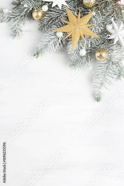 Fototapeta Christmas and New Year background with holiday decorations.
 Branch of fir tree with Сhristmas ornaments on old white wooden shabby background with empty space for text.