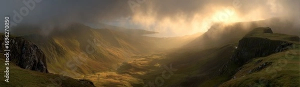 Obraz A dramatic, moody landscape with rolling hills, enveloped in fog, and illuminated by a burst of golden light