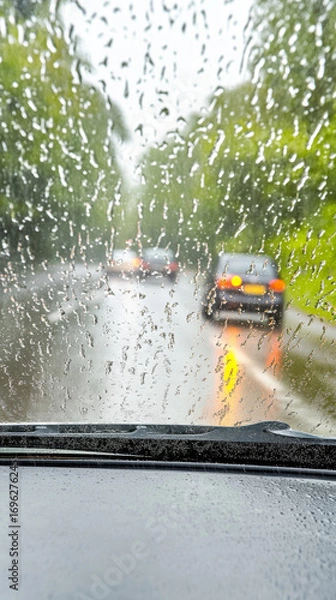 Obraz Rain streams down the car windshield, blurring the outside world.