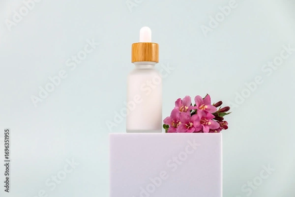 Fototapeta bottle of essential oil with a pipette on a white podium. The concept of skin care using natural cosmetics