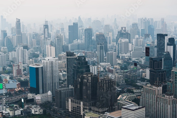 Fototapeta Cityscape of crowded financial skyscraper and urban building in hazy weather during early morning at Bangkok downtown