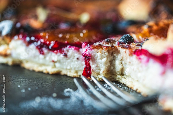 Fototapeta A delicious berry dessert, a piece of tart or an open sweet pie with figs, blueberries and apricots on a black plate. High quality photo