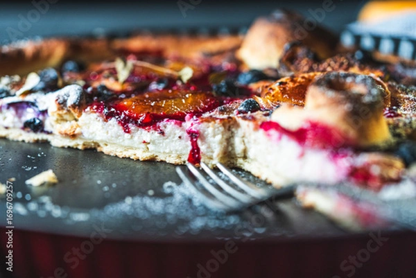 Fototapeta A delicious berry dessert, a piece of tart or an open sweet pie with figs, blueberries and apricots on a black plate. High quality photo