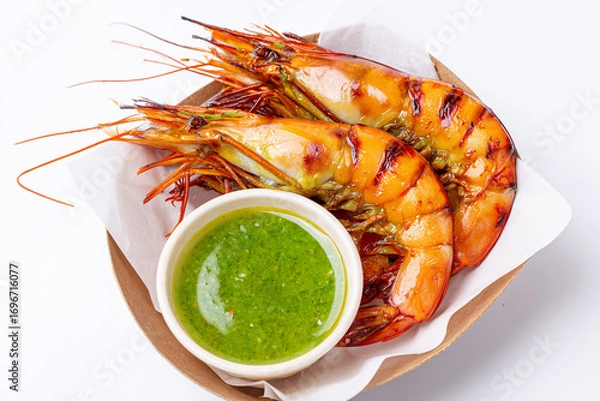 Fototapeta Boiled shrimp served in a takeout box with spicy green seafood dipping sauce. Isolated on white background, highlighting the fresh prawns, vibrant sauce, and glossy texture, Grilled prawn in carton 
