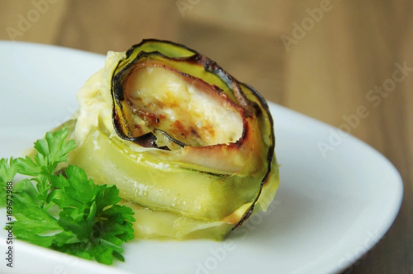 Obraz Roll of zucchini roasted with cheese and ham. Wooden background. Close up view.
