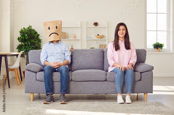 Fototapeta Couple family problems, man wearing paper bag head face to express negative emotion, insulting and offensive wife, feeling sad, suffering from bad relationship or break up, feeling lonely and sad