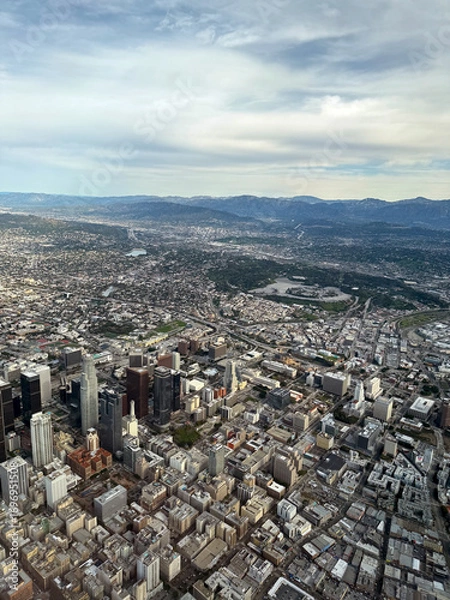 Fototapeta aerial view of downtown Los Angeles - airplane view of Southern California city skyline and mountains in the distance, cloudy summer sky