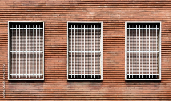 Fototapeta Window bars and closed windows on a bricks wall