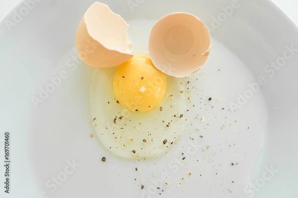 Fototapeta Raw broken eggs with seasoning