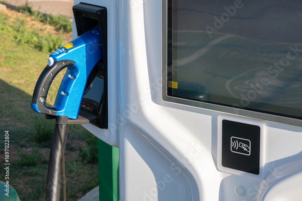 Fototapeta electric vehicle charging nozzle is in its holster at the station. The station also features a screen and a contactless payment terminal for a credit card