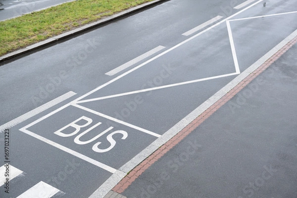 Fototapeta Road marking of a bus stop is painted on wet asphalt. The scene represents European road infrastructure in an urban environment