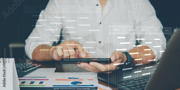 Fototapeta A businessman uses a tablet at a desk, interacting with virtual data dashboards and charts representing analytics and digital workflow.