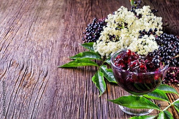 Fototapeta Toasts with elderberry jam and fresh berry fruits on wooden table. Free space for your text.