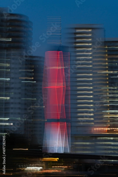 Fototapeta Artistic motion blur photo of Menara 118 illuminated in red at night, surrounded by nearby high-rise buildings in Kuala Lumpur, Malaysia.