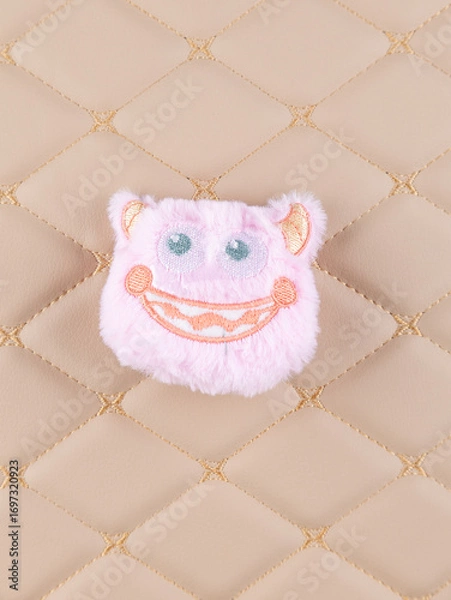 Fototapeta Close-up of a fluffy pink monster plush with a cheerful smile and adorable horn-like ears