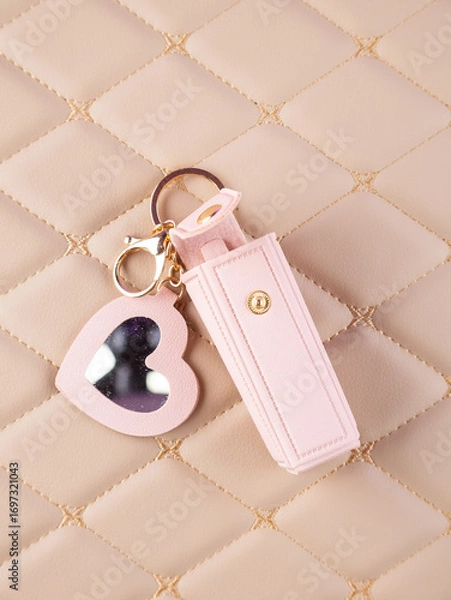 Fototapeta Close-up of a pink leather lipstick case with a heart-shaped mirror, elegantly placed on a  beige background