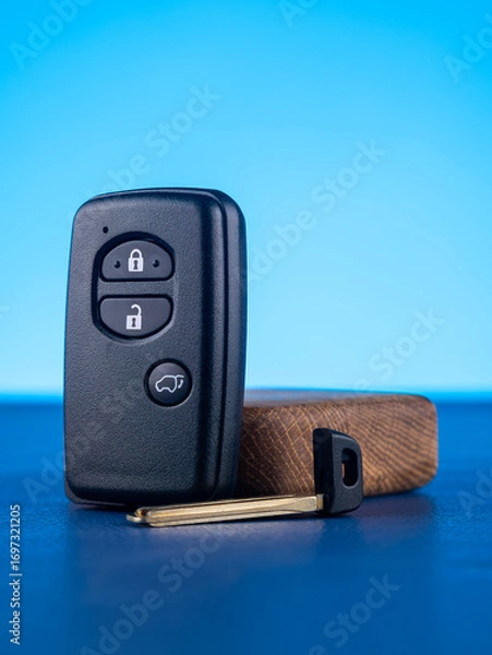 Fototapeta Close up of black car key with open and close buttons on blue background