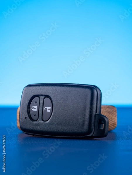 Fototapeta Close up of black car key with open and close buttons on blue background
