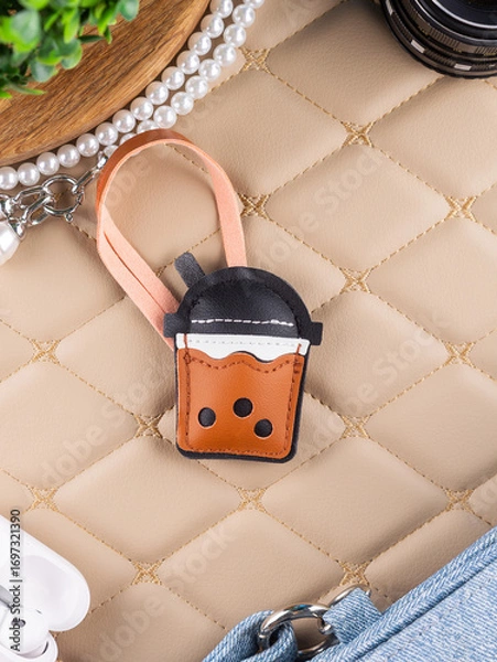 Fototapeta Close up of leather bag keychain in the shape of a glass of bubble tea on beige table
