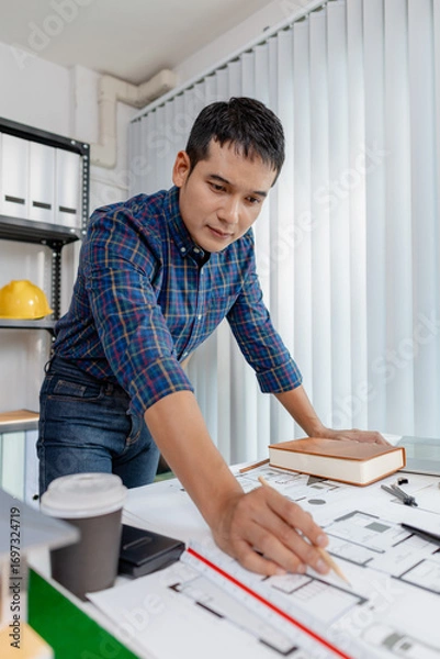 Fototapeta Young architect working in office with building models and floor plans, analyzing details and creating innovative design concepts, showing creativity, focus, and dedication in architecture projects.