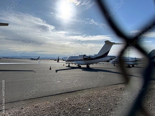 Obraz airplane at the airport through a chain link fence - general aviation airfield with jet planes on the tarmac