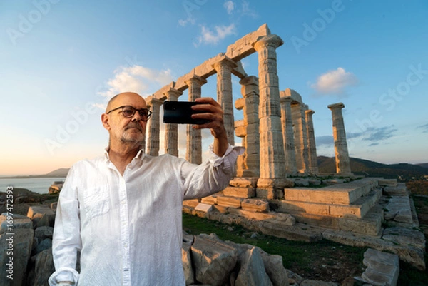 Obraz Man Photographing Ancient Ruins at Sunset with a Smartphone