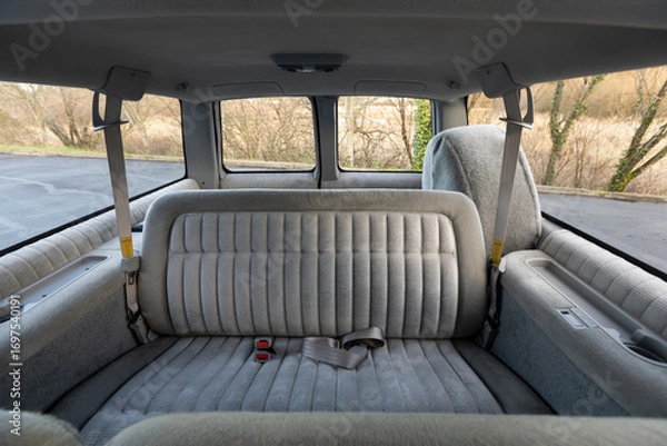 Fototapeta 1994 full size American 4x4 SUV interior with gray cloth seats, foldable seating rows, seat adjustment handles, rear passenger space, and built in cup holders showing classic cabin design
