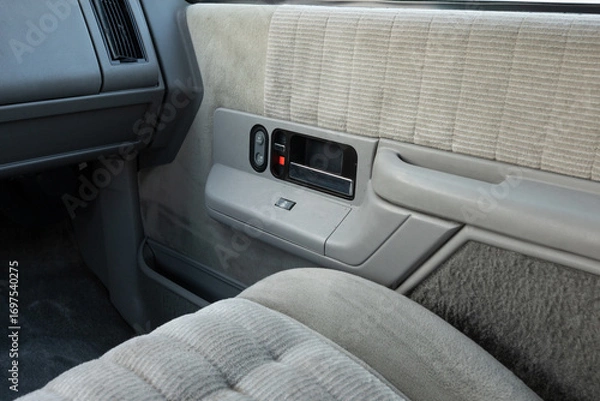Fototapeta 1994 full size American 4x4 SUV interior with gray cloth seats, foldable seating rows, seat adjustment handles, front passenger space, and built in cup holders showing classic cabin design
