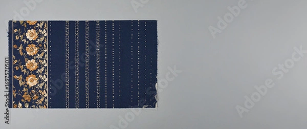 Fototapeta A refined blue fabric swatch with a rich gold floral border on one side, complemented by subtle vertical stripes of gold dots, elegantly presented on a sophisticated grey background.