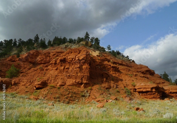 Fototapeta Red rock of Wyoming, with prairie grass and beautiful skis. Geology of the area includes many types of rock.