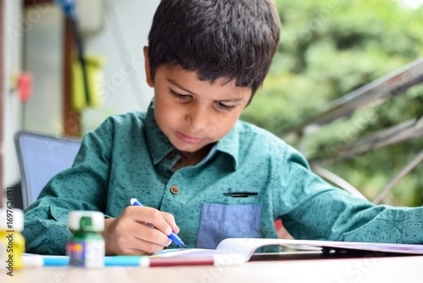 Fototapeta Smart Indian little boy perform thumb painting with different colourful water colour kit during the summer vacations, Cute Indian Kid doing colourful thumb painting drawing on wooden table