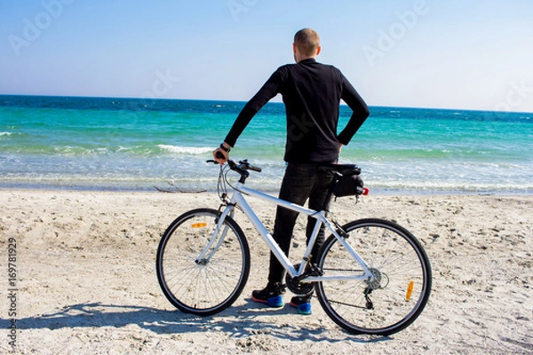 Fototapeta Bicycle rider relaxing on the beach in good weather 