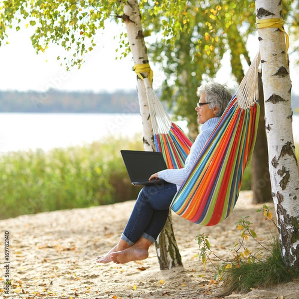 Fototapeta Cozy Autumn Vibes: Senior Using a Laptop by the Lake