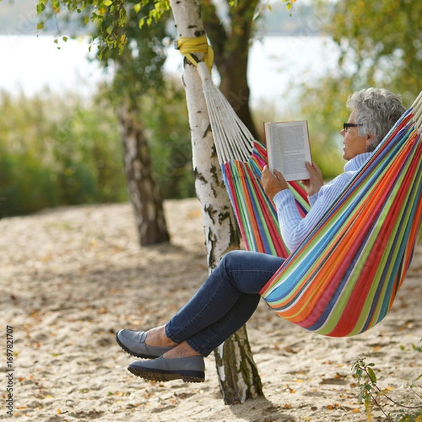 Fototapeta Tranquil Autumn Escape: Senior Reading by the Lake
