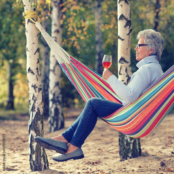 Fototapeta Autumn Serenity: Senior Relaxing in a Hammock with Wine