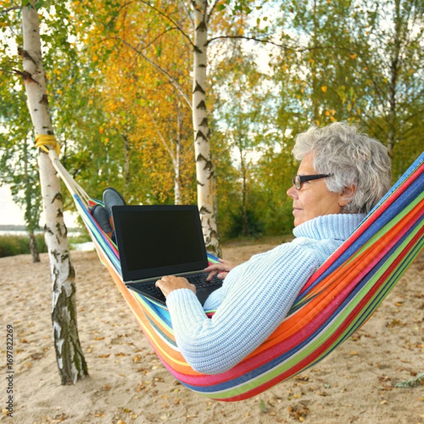 Fototapeta Tranquil Autumn Escape: Senior Relaxing with a Laptop by the Lake