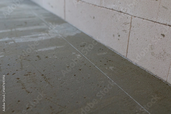 Fototapeta Concrete floor screed pouring and processing. Unfinished interior surfaces. Walls and floor without finishing. Сoncept of construction engineering development. Construction and engineering