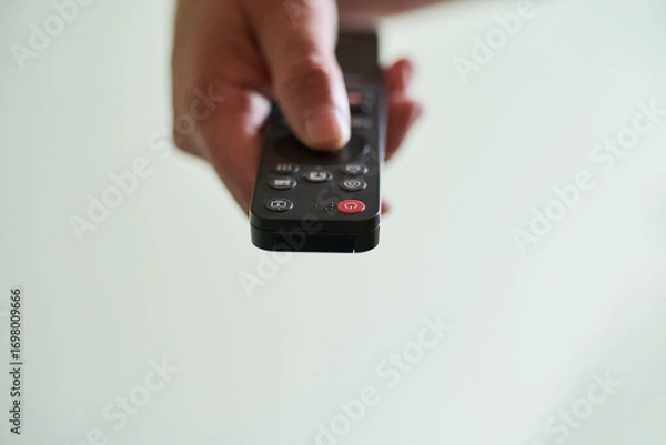 Obraz Hand holding a remote control indoors