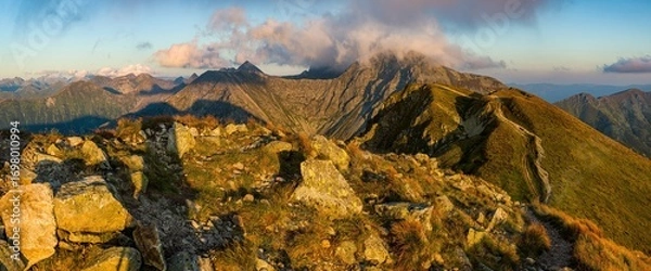 Fototapeta A sweeping golden sunset panorama captures the rugged ridge of Salatín (2,047 m), its rocky slopes bathed in warm light, clouds gathering over peaks, looking out across the Western Tatras’ dramatic al