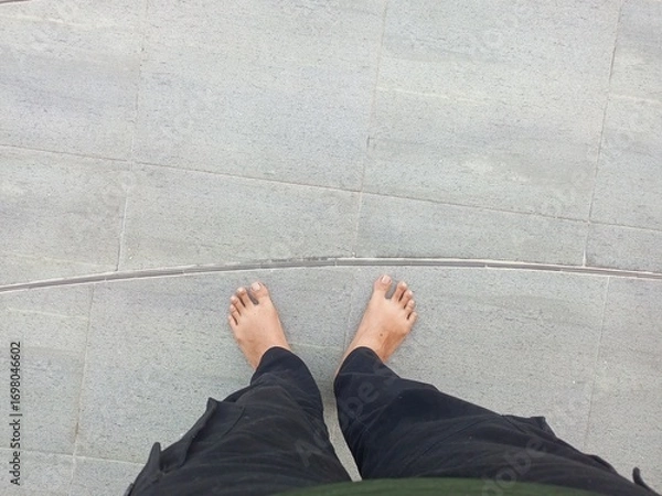 Fototapeta First Person View of A Man Standing Barefoot on a Floor