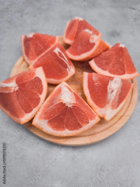 Fototapeta Fresh grapefruit wedges arranged on wooden plate, capturing the essence of citrus delight