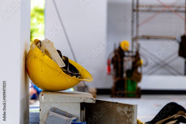 Fototapeta Yellow safety helmet on construction site with worker in background