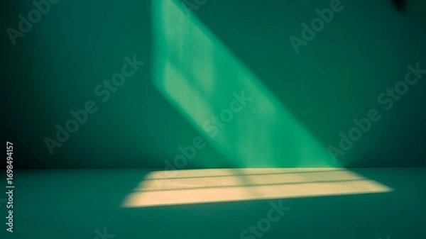Fototapeta A bright beam of light from a window shines on a teal wall and floor. The resulting contrast creates an interesting interplay of light and shadow.