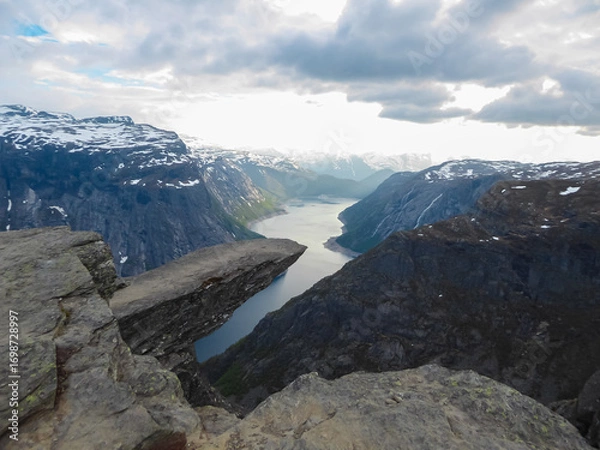 Obraz The world-famous Trolltunga rock formation juts out horizontally from a massive cliff, high above the serene blue fjord below, showcasing one of Norway's most spectacular and iconic natural landmarks.