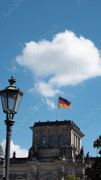 Fototapeta Horizontal photograph of the German flag waving in the breeze on a blue-sky day.
