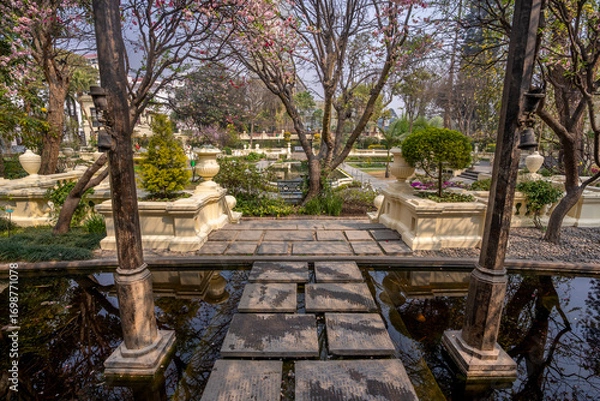Fototapeta Tranquil view of the Garden of dreams in Kathmandu, Nepal. Beautiful landscaped garden with stone pathways, water fountains, blooming trees and elegant classical architecture offering a serene escape.