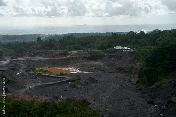 Obraz A stone quarry in Indonesia. Large equipment such as bulldozers and dump trucks are working on the site.